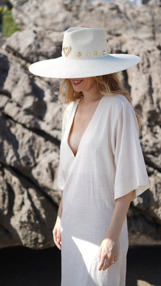 El Sombrero Panamá Charlotte es una pieza diseñada para destacar. Su ala ancha y su silueta estructurada crean una presencia sofisticada y muy favorecedora, mientras que los delicados apliques dorados aportan un toque distintivo que eleva cualquier look con naturalidad.
